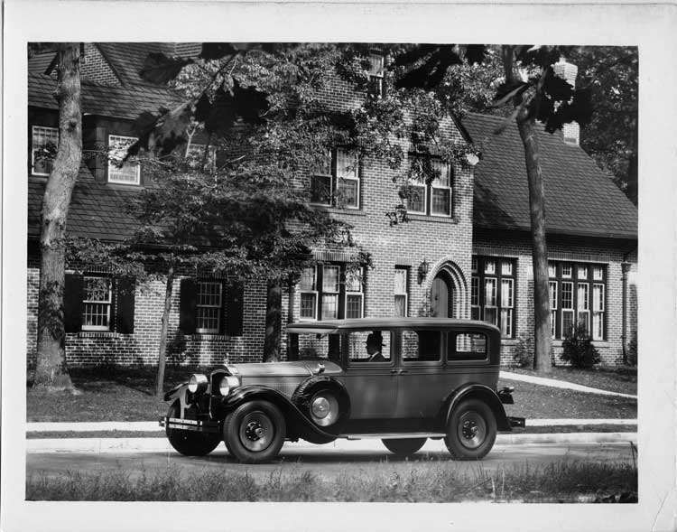 1928 Packard sedan, seven-eights left front view, on residential street, male behind wheel