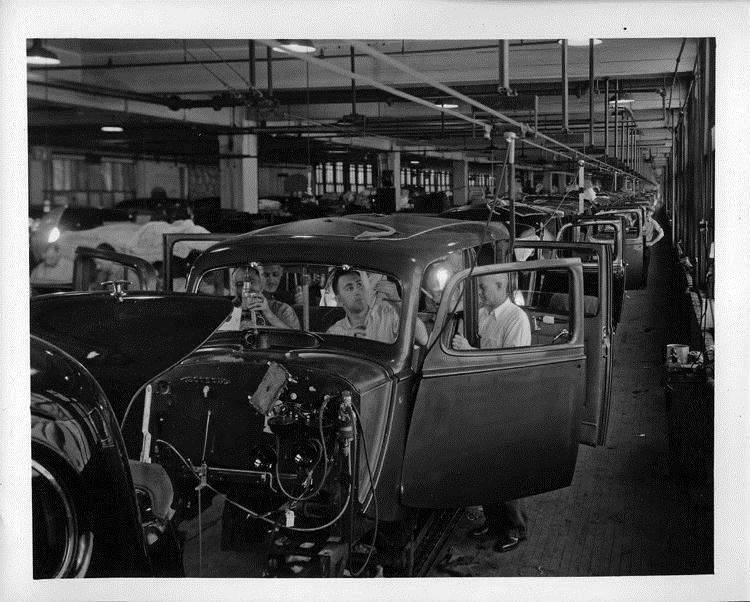 Production line picture, several touring sedan bodies can be seen with workers