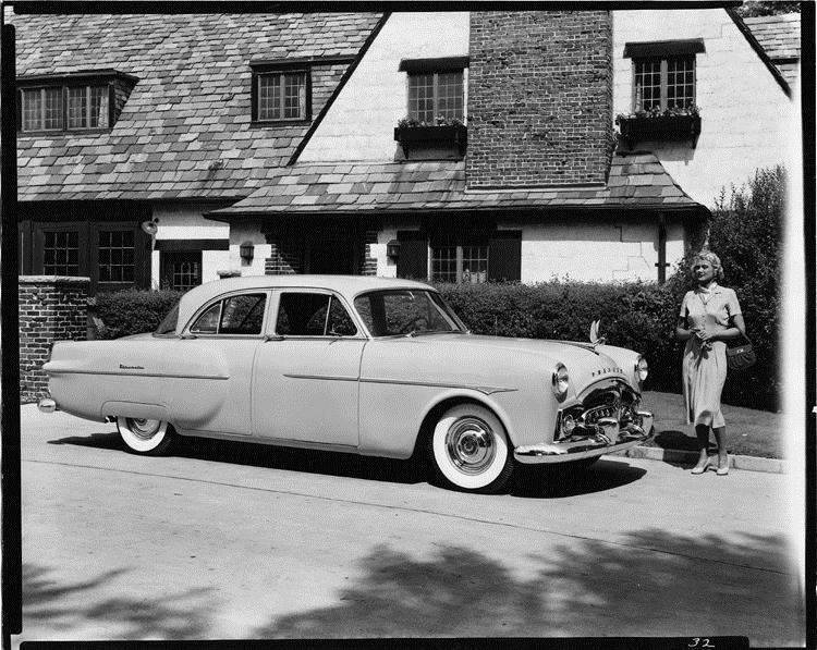 1951 Packard sedan, parked in driveway in front of house, female standing by car