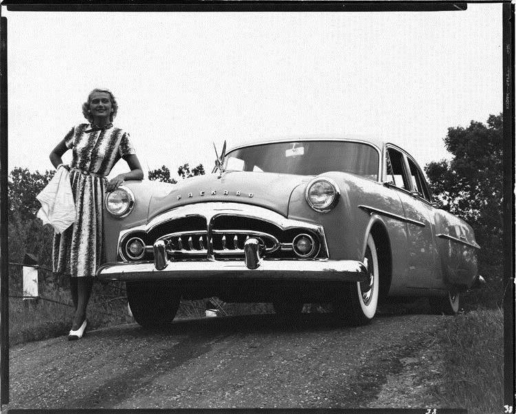1951 Packard 300 sedan, front view, parked on hill, female leaning on front left side
