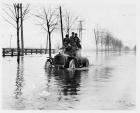 1905 Packard on water-covered road with seven men aboard
