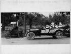 1899 Packard Model A roadster with 1913 Packard 48 touring car, on street with passengers