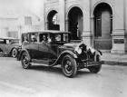 1920 Packard on street, female driver, in front of stone building