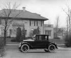 1921 Packard coupe parked on street in front of large home