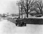 1920-1921 Packard touring car driving up a snowy hill by stone wall