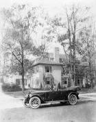 1920-1923 Packard touring car in front of large home, Alvan Macauley in driver's seat