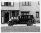 1925 Packard sedan, left side view, male chauffeur, parked in front of large home