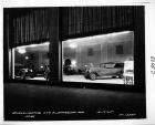 1925 Packards in dealership showroom, through window at night
