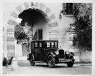 1925 Packard sedan parked under stone archway of large house