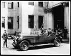 1925-1926 Packard touring car with American flag parked in front of large stone building