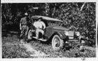 1925-1926 Packard sport model, front view, top raised, two men standing at side, on jungle road