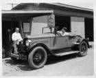 1925-1926 Packard runabout, actress Leatrice Joy behind wheel in front of a Packard service station
