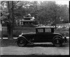 1927 Packard coupe, left side view, parked on street, garden in background