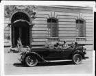 1928 Packard touring car parked on street with male chauffeur