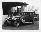 1928 Packard sedan limousine parked in front of house, couple standing at passenger side
