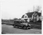 1930 Packard sedan parked on street in front of large home