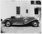 1930 Packard roadster, right side view, top folded, parked by building