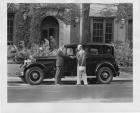 1931 Packard sedan, left side view, parked on street, two men shaking hands at side of car