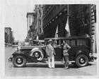 1932 Packard sedan, left side view, parked on city street, two men standing at side