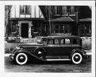 1932 Packard sedan, left side view, parked on street in front of brick house