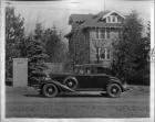 1933 Packard coupe, left side view, parked on street, brick house in background