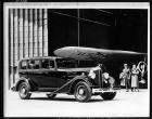 1934 Packard sedan with U.S. mail plane at airplane hangar
