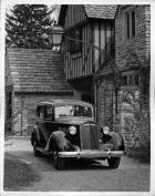 1937 Packard touring sedan, three-quarter front view, parked in driveway of home