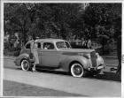 1939 Packard touring sedan parked on street, female at front passenger door