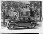1939 Packard touring sedan, parked on street in front of house, family at front door