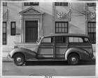 1939 Packard station wagon, left side view, parked on street in front of stone building