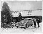 1939 Packard convertible sedan parked in front of ski lodge with family