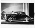 1942 Packard convertible coupe, top folded, female behind wheel, man standing at passenger door