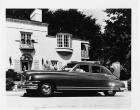 1948 Packard touring sedan, parked on street in front of home with couple