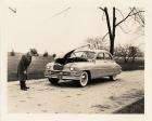 1950 Packard sedan, hood raised, man inspecting front of car