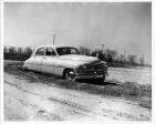 1950 Packard touring sedan on rutted dirt road, man behind wheel