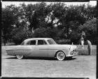 1951 Packard 300 sedan parked on grass, couple playing golf in background