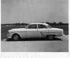 1953 Packard sedan, left side view, parked on drive, cars in distance