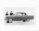 1954 Packard 2-door sedan, left side view, well dressed couple standing at front passenger side
