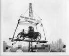 1899 Packard hoisted above Detroit skyline